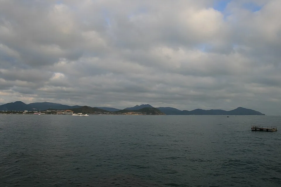 Hainan adasında Sanya, Dadonghai'den bulutlu havada deniz ve karşı kıyı görünümü.
